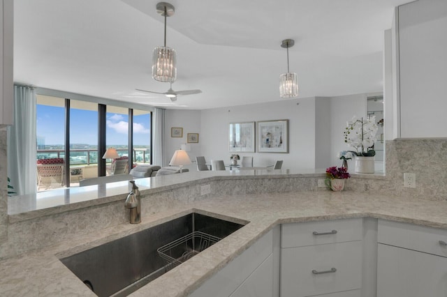 kitchen with tasteful backsplash, ceiling fan, sink, pendant lighting, and white cabinets