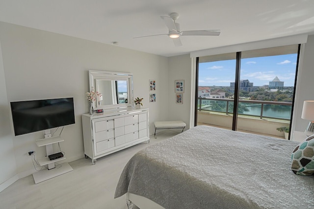 bedroom featuring ceiling fan, floor to ceiling windows, and a water view