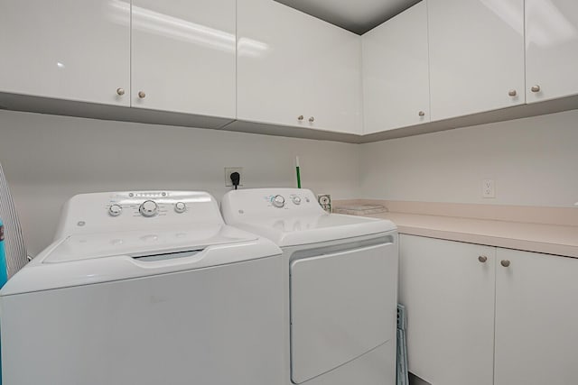 washroom with cabinets and washing machine and clothes dryer