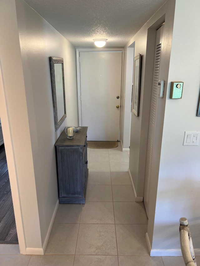 hall featuring light tile patterned floors and a textured ceiling