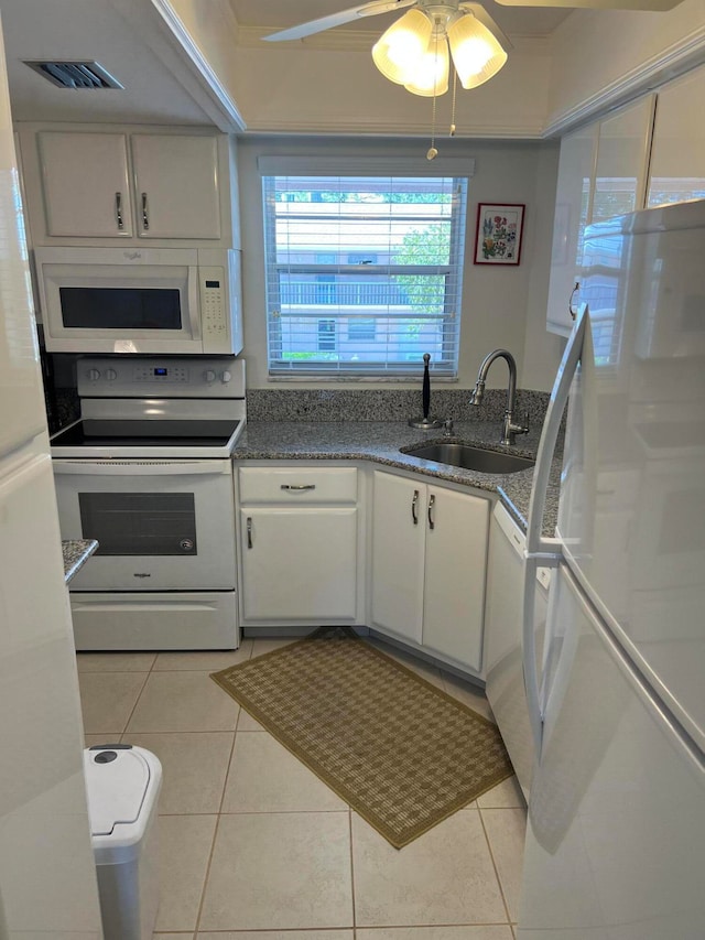 kitchen with white appliances, white cabinets, sink, dark stone countertops, and light tile patterned floors