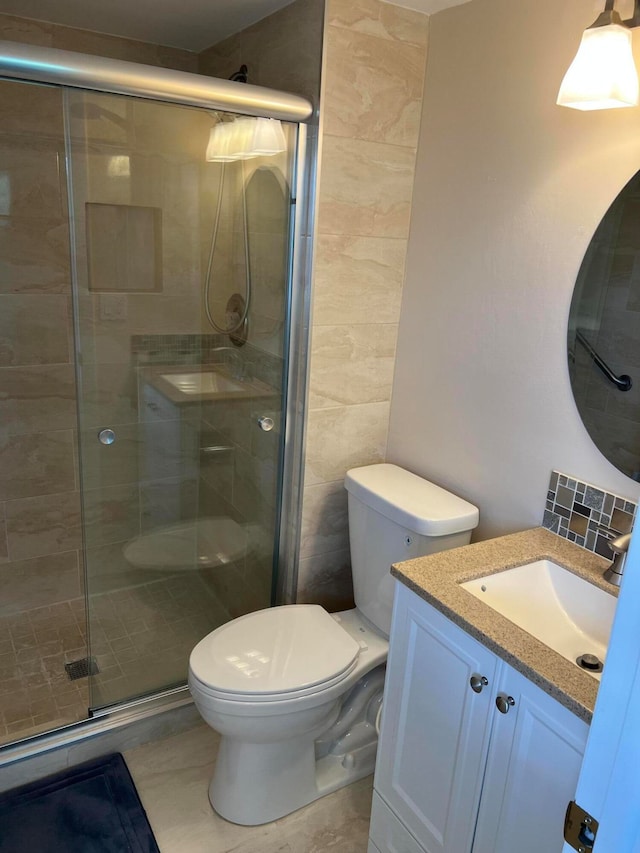 bathroom featuring vanity, toilet, and a shower with shower door