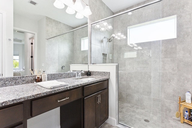 bathroom with a wealth of natural light, a shower with door, and vanity