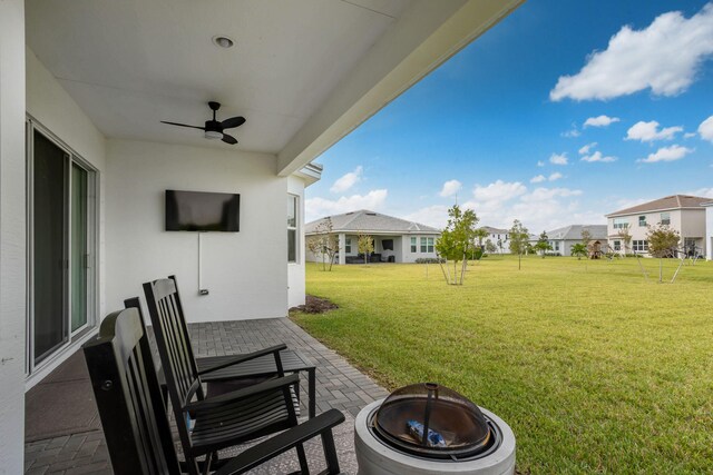 view of yard featuring ceiling fan, an outdoor fire pit, and a patio