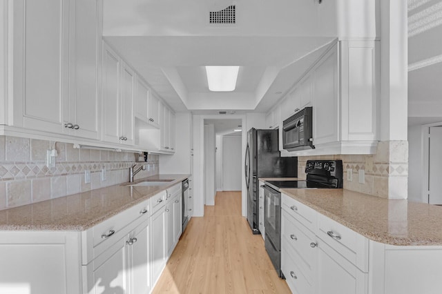 kitchen featuring sink, light hardwood / wood-style flooring, white cabinetry, and black appliances