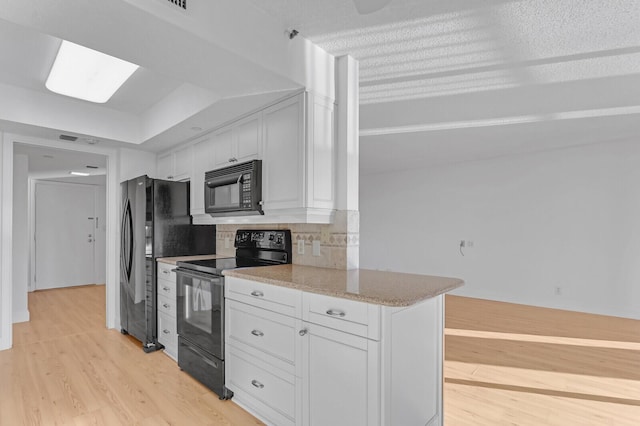 kitchen featuring black appliances, decorative backsplash, light hardwood / wood-style floors, light stone counters, and white cabinetry