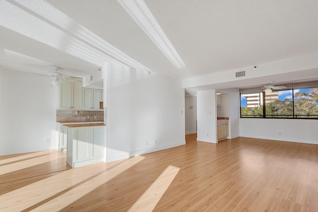 unfurnished living room with a textured ceiling, light hardwood / wood-style floors, and ceiling fan