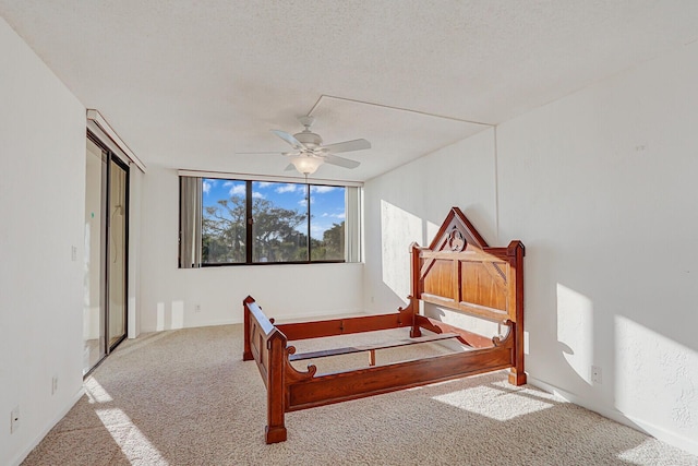 carpeted bedroom with ceiling fan and a textured ceiling