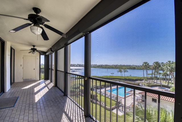 unfurnished sunroom featuring ceiling fan and a water view