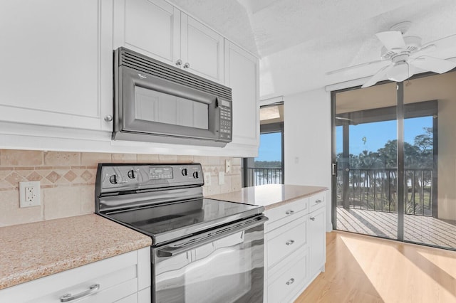 kitchen with backsplash, light stone counters, black appliances, light hardwood / wood-style floors, and white cabinetry