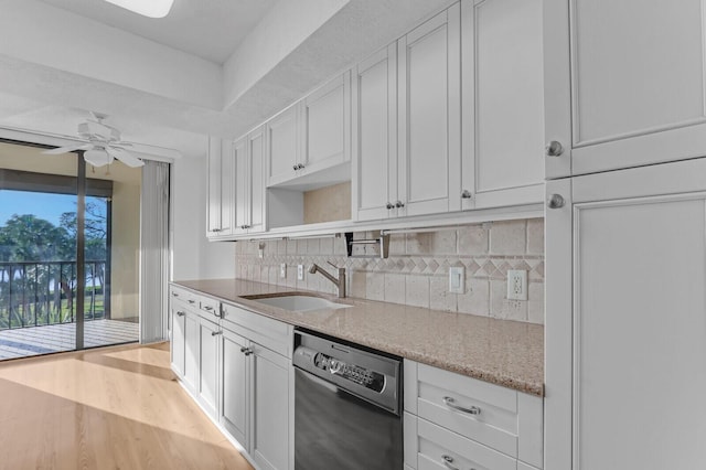 kitchen with stainless steel dishwasher, white cabinetry, sink, and light hardwood / wood-style flooring