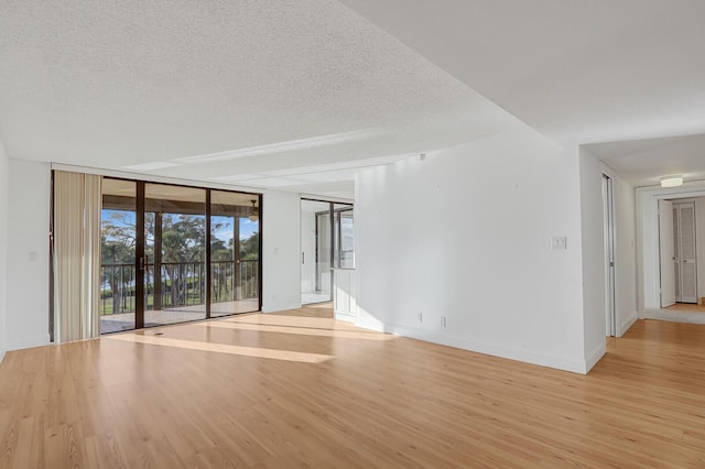 unfurnished room with expansive windows, light hardwood / wood-style floors, and a textured ceiling