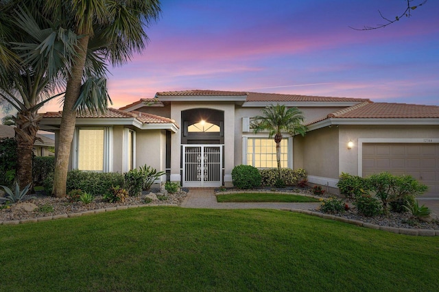 mediterranean / spanish-style home featuring a lawn, french doors, and a garage