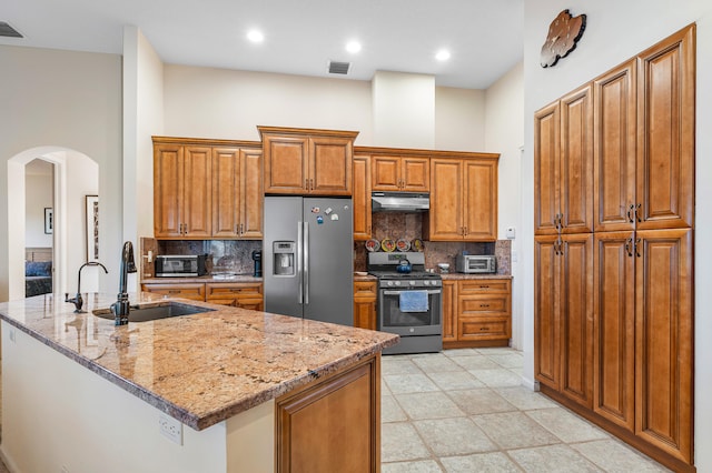 kitchen featuring decorative backsplash, stainless steel appliances, light stone counters, and sink