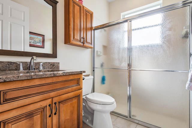 bathroom with tile patterned flooring, vanity, toilet, and a shower with shower door