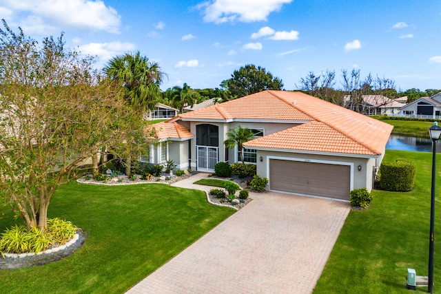 mediterranean / spanish-style home with a garage, a water view, and a front lawn