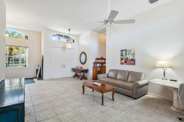 living room with ceiling fan and a towering ceiling