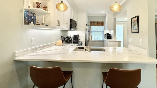 154 Lake Meryl Dr Unit 257, West Palm Beach, FL 33411 - kitchen with stainless steel appliances, a peninsula, hanging light fixtures, white cabinets, and ornamental molding