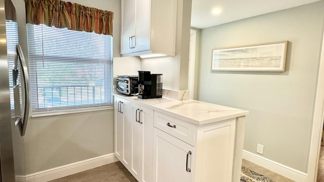 154 Lake Meryl Dr Unit 257, West Palm Beach, FL 33411 - kitchen with light stone counters, white cabinets, and stainless steel fridge