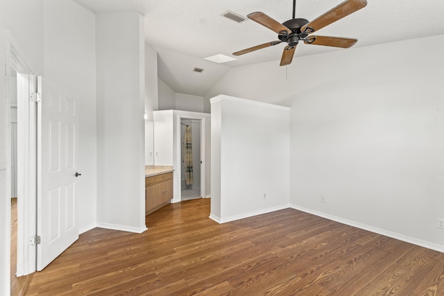 unfurnished bedroom featuring dark hardwood / wood-style flooring, ensuite bath, vaulted ceiling with skylight, a textured ceiling, and ceiling fan