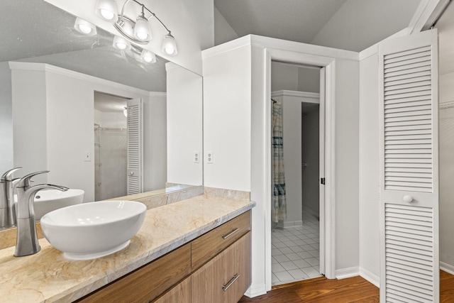 bathroom featuring hardwood / wood-style flooring, vanity, a textured ceiling, and vaulted ceiling