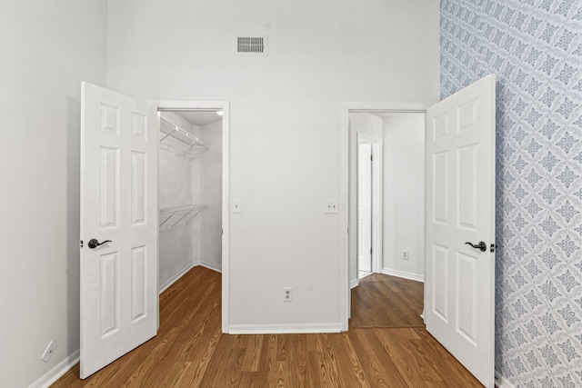 unfurnished bedroom with a spacious closet, a closet, and hardwood / wood-style flooring