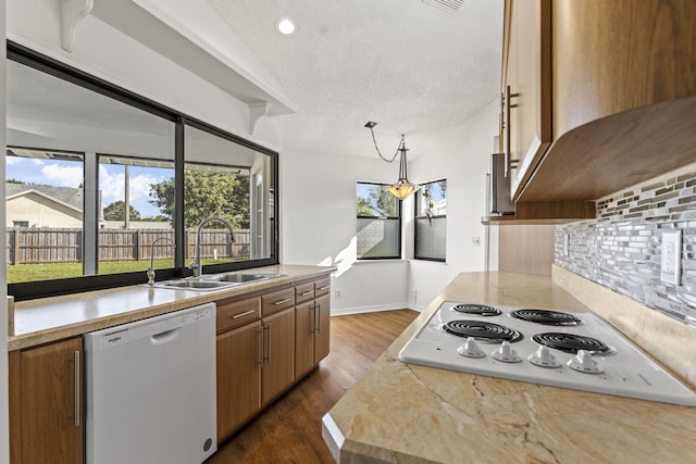 kitchen featuring pendant lighting, sink, white appliances, and a textured ceiling