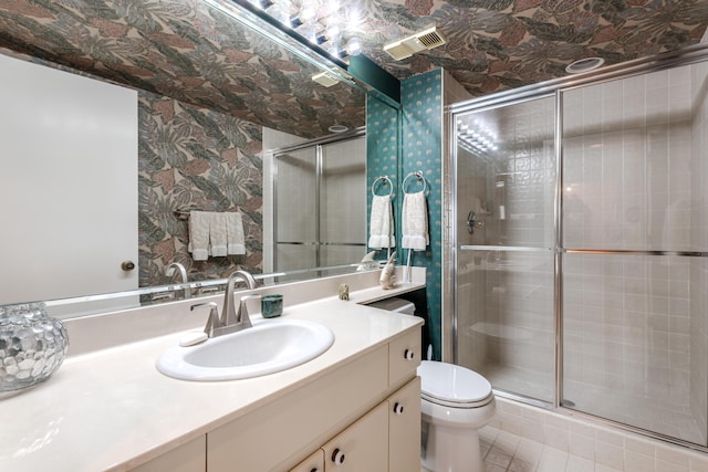 bathroom with tile patterned flooring, vanity, an enclosed shower, and toilet