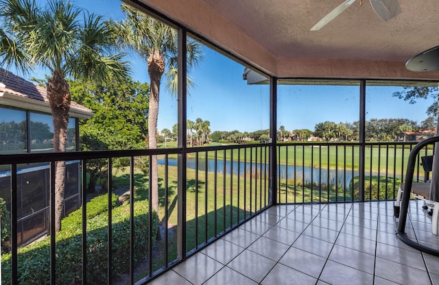 unfurnished sunroom featuring ceiling fan and a water view