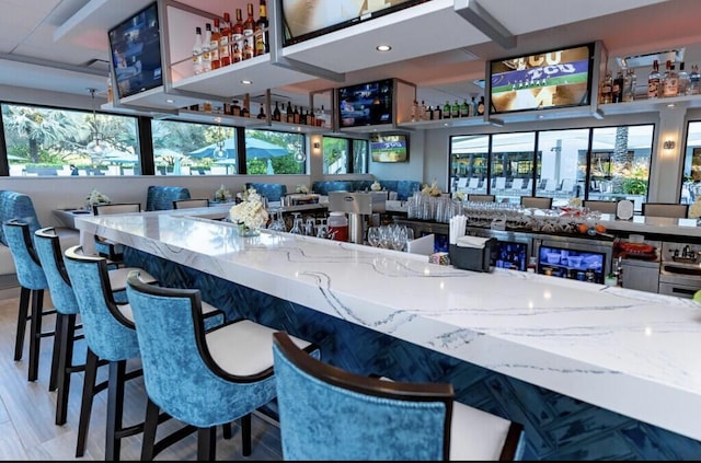 bar with light stone countertops and hardwood / wood-style flooring