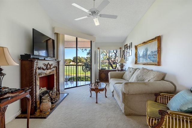 living room with ceiling fan, light colored carpet, a textured ceiling, vaulted ceiling, and a fireplace