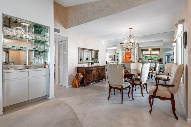 dining area with a textured ceiling, a notable chandelier, light tile patterned flooring, and sink