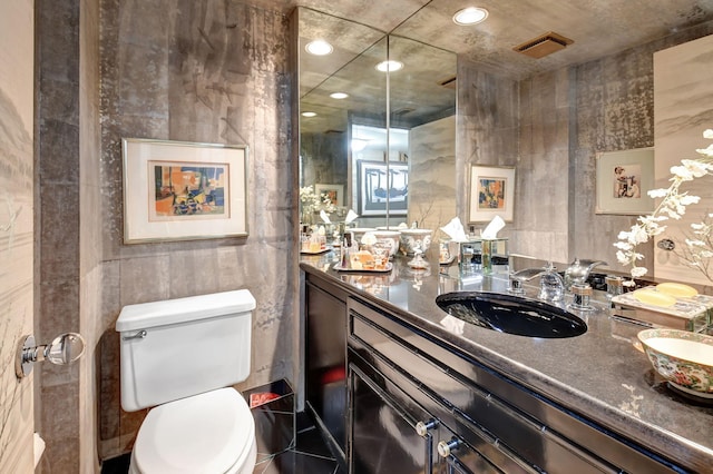 bathroom featuring vanity, toilet, and tile walls