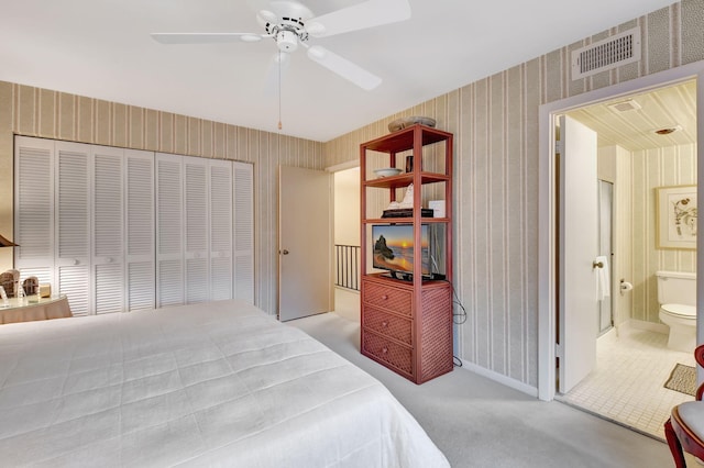 bedroom with connected bathroom, ceiling fan, a closet, and light colored carpet