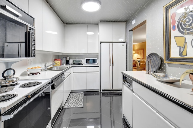 kitchen with white cabinetry, white appliances, and sink