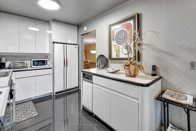 kitchen featuring dark tile patterned flooring, white appliances, and white cabinetry