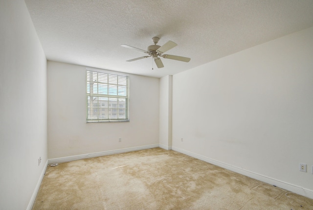 empty room with ceiling fan, light colored carpet, and a textured ceiling