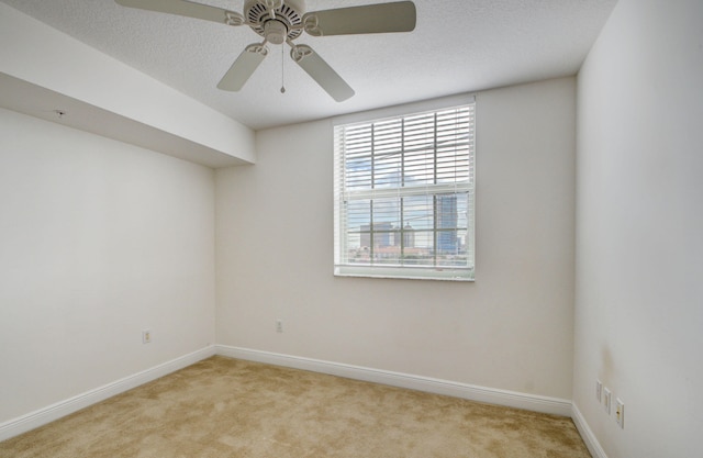 carpeted spare room with a textured ceiling and ceiling fan