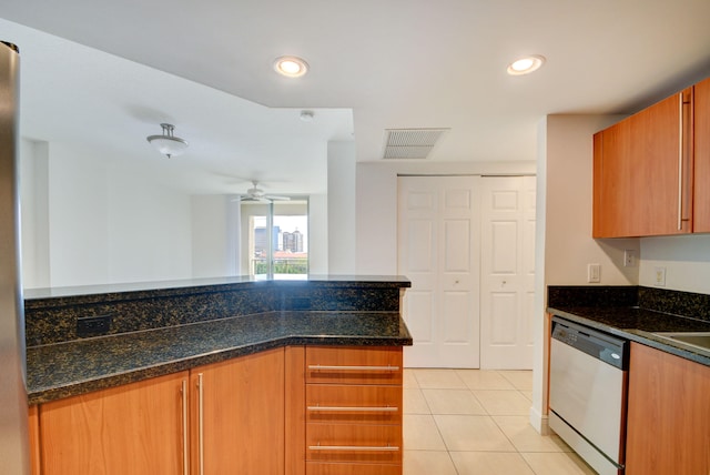 kitchen with dishwasher, dark stone counters, ceiling fan, light tile patterned floors, and kitchen peninsula