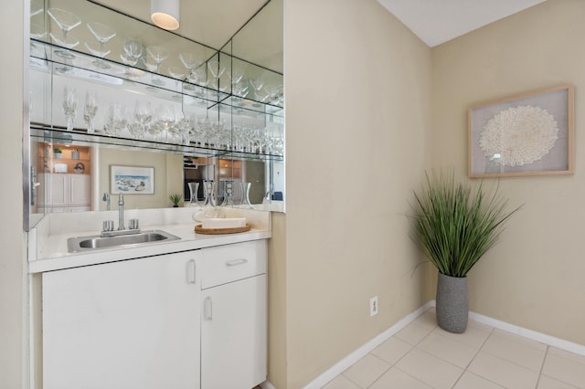 bar featuring white cabinetry, sink, and light tile patterned flooring