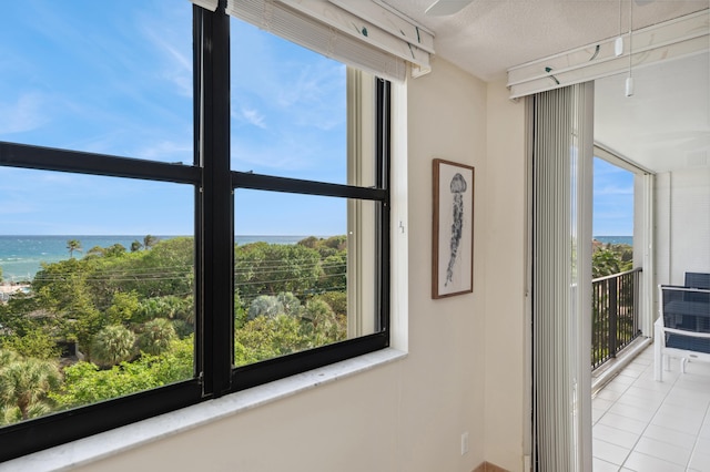 interior details with a textured ceiling, a water view, and tile patterned floors