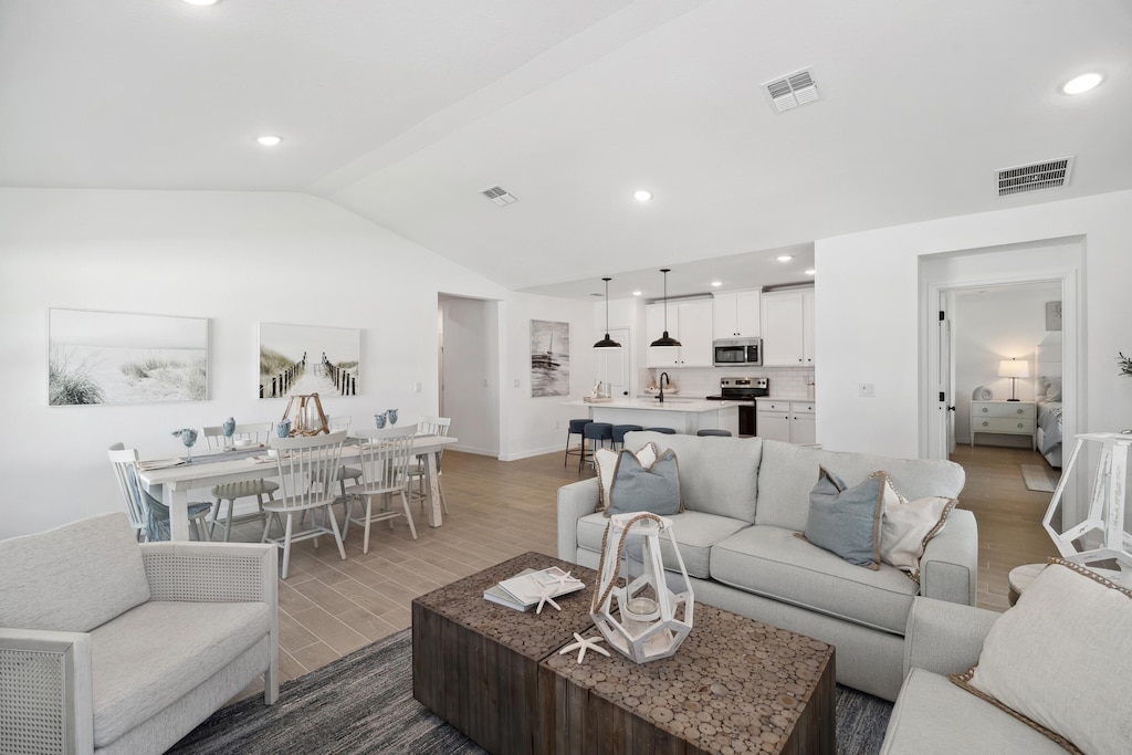 living room with wood-type flooring, lofted ceiling, and sink