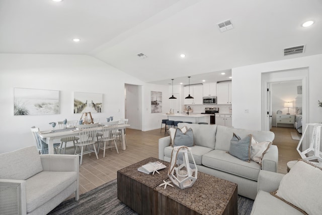 living room with wood-type flooring, lofted ceiling, and sink