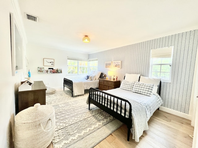 bedroom with light wood-type flooring, multiple windows, and crown molding