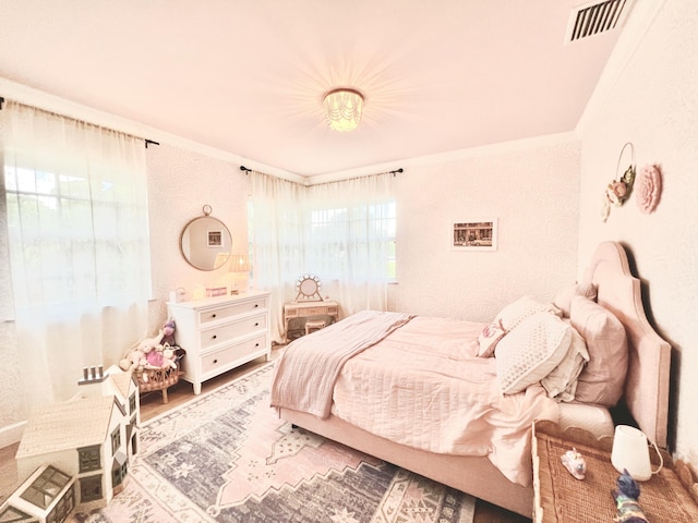 bedroom featuring wood finished floors, visible vents, and crown molding