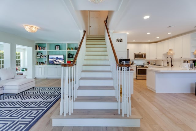 stairway with wood finished floors and recessed lighting