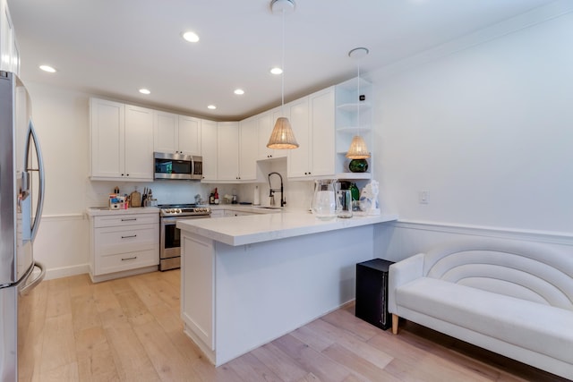 kitchen featuring stainless steel appliances, a peninsula, light wood-style flooring, and white cabinetry