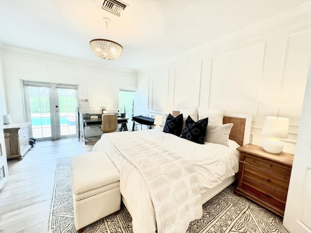 bedroom with access to exterior, french doors, light hardwood / wood-style floors, a chandelier, and ornamental molding