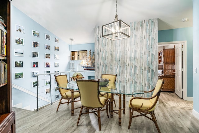 dining space featuring lofted ceiling, light hardwood / wood-style floors, and an inviting chandelier