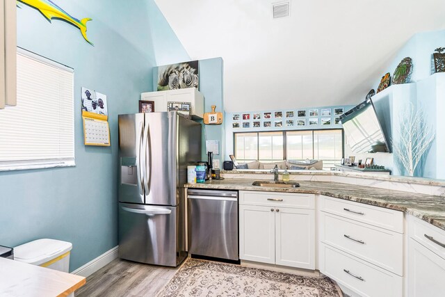 kitchen featuring sink, light stone counters, light hardwood / wood-style flooring, appliances with stainless steel finishes, and white cabinets